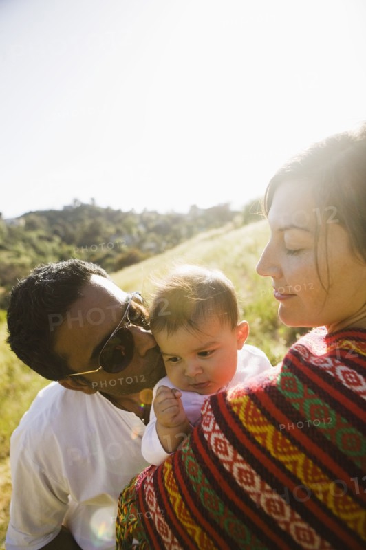 Mother watching father kissing baby