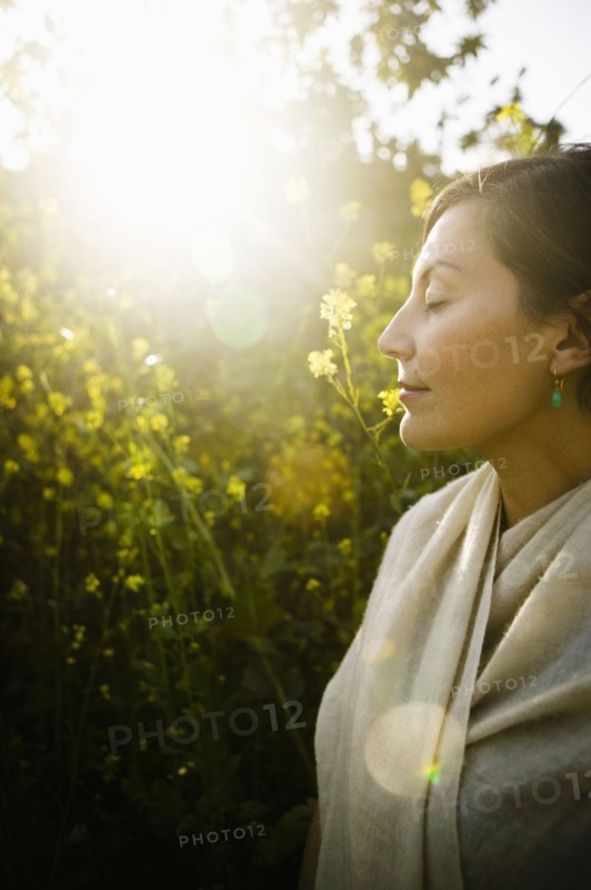 Mixed race woman with eyes closed in field