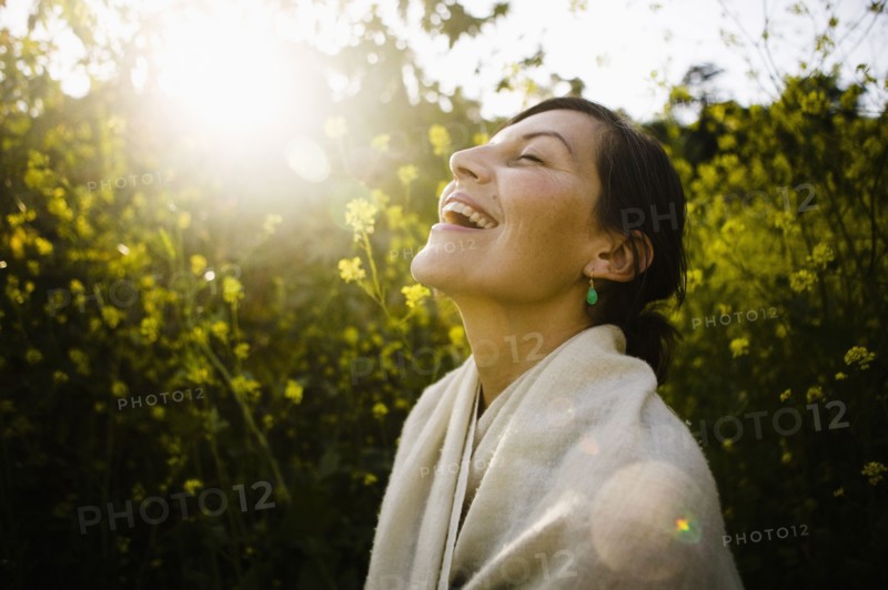 Laughing mixed race woman with eyes closed in field