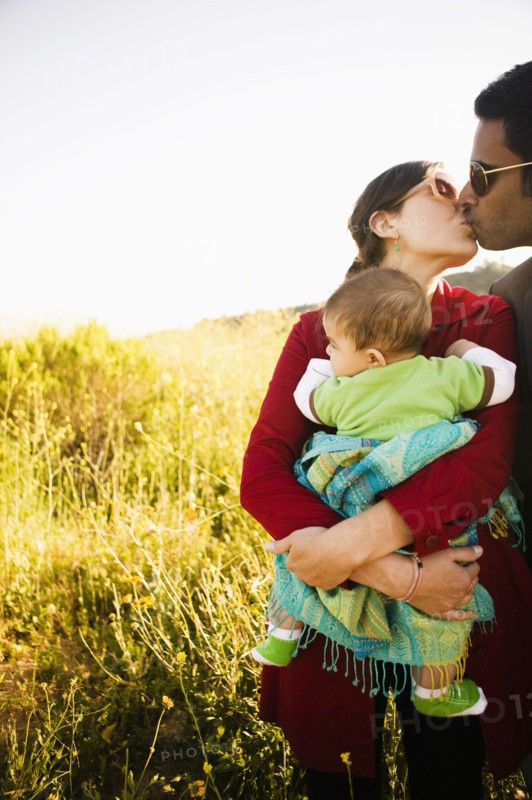 Mother holding baby and kissing husband