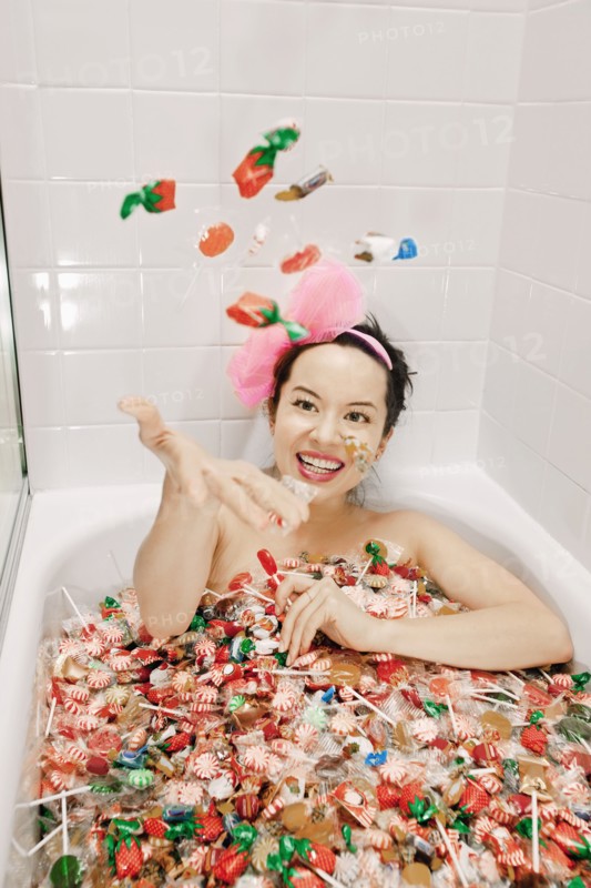 Mixed race woman taking a bath in candy