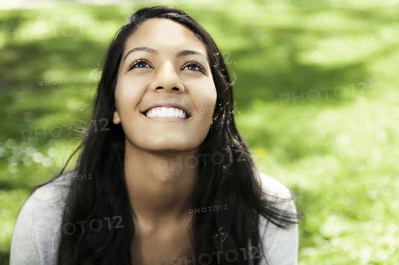 Smiling Hispanic teenager sitting in grass