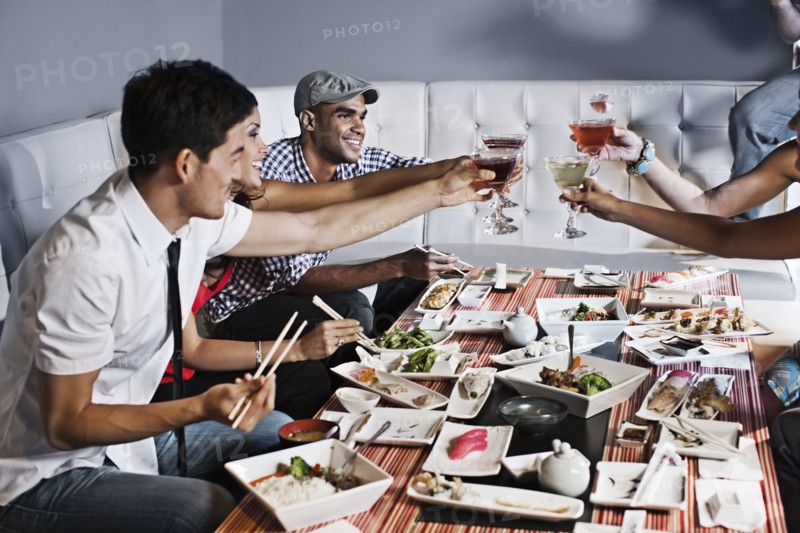 Friends toasting and eating together in restaurant