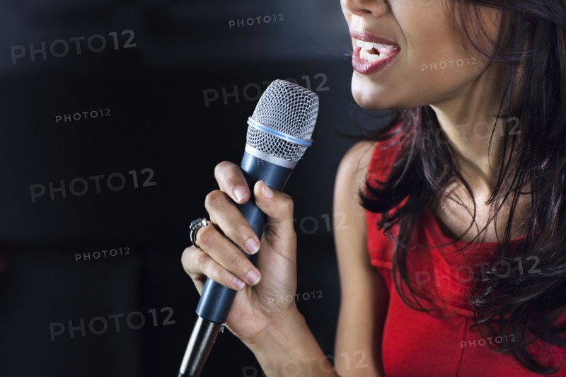 Mixed race woman singing karaoke in nightclub