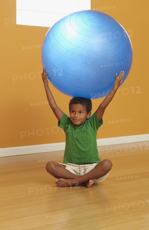 Mixed race boy lifting exercise ball