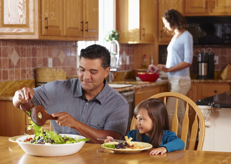 Father serving daughter salad