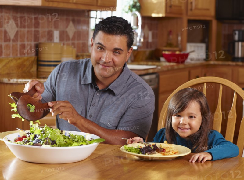 Father serving daughter salad