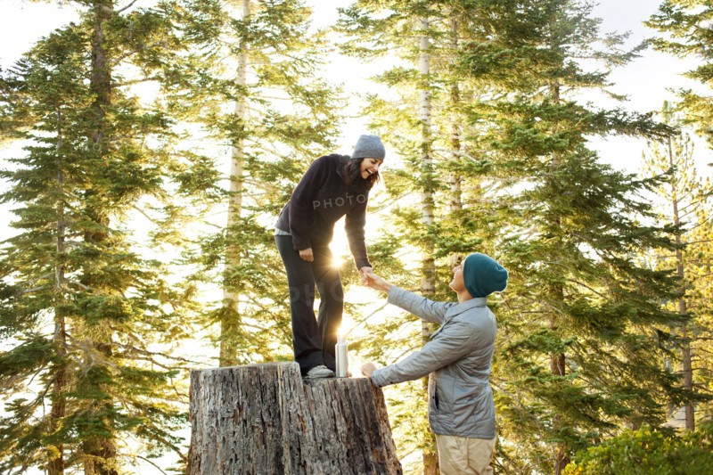 Couple playing on tree stump in forest