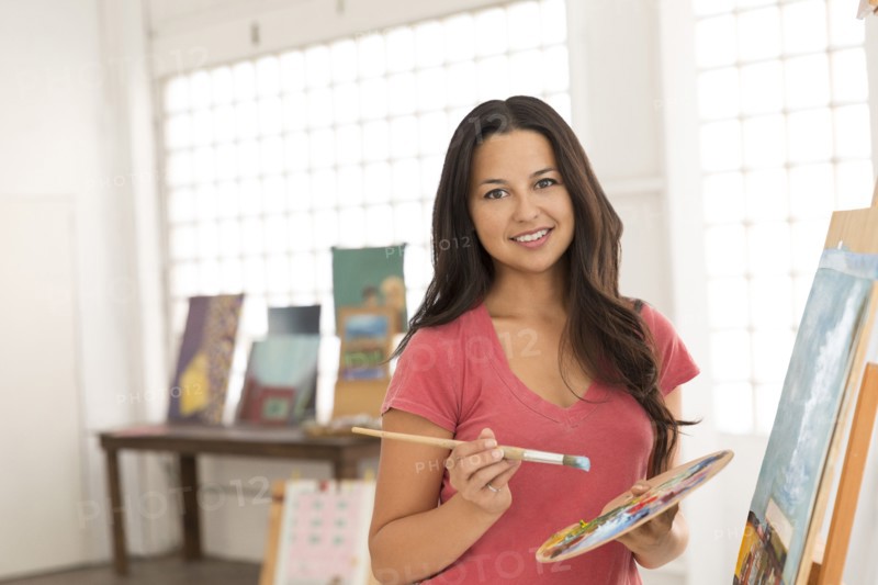 Portrait of smiling woman painting at easel
