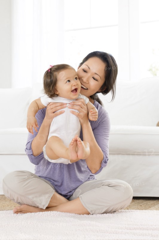Mother playing with baby girl in living room