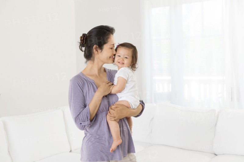Mother holding baby girl in living room