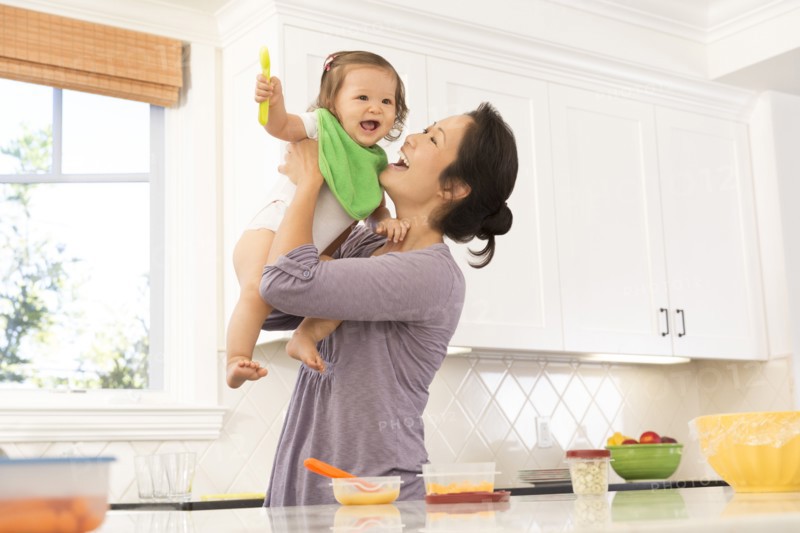 Mother holding baby girl in kitchen