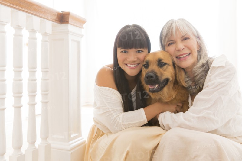 Mother and daughter hugging dog on steps