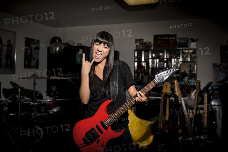 Woman playing electric guitar in basement