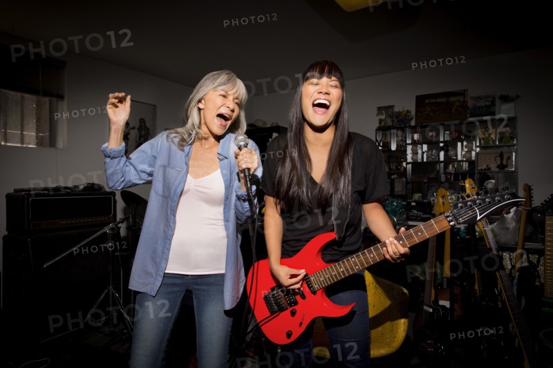 Mother and daughter playing music guitar in basement