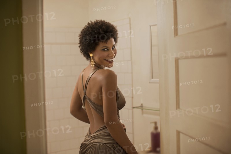 Woman in dress smiling in bathroom
