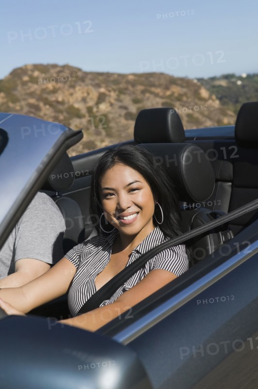 Asian woman driving convertible car