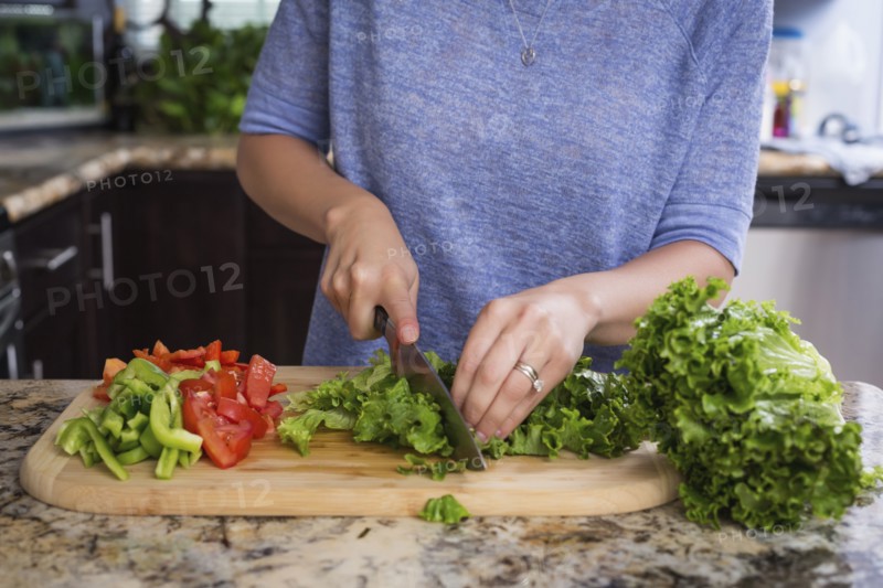 Mixed race woman chopping vegetables in kitchen