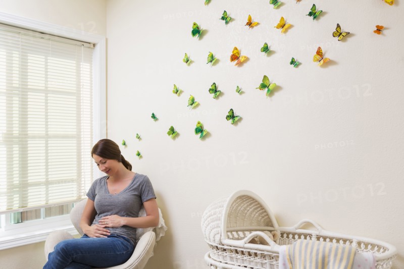 Mixed race pregnant woman sitting in nursery
