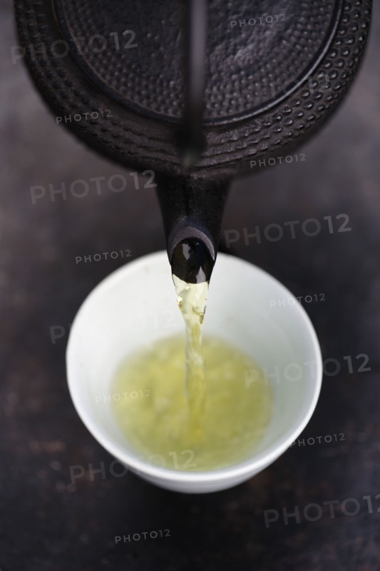 Close up of Japanese green tea being poured from teapot into cup