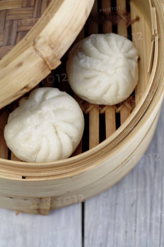 Close up of steamed dim sum pork buns in bamboo basket
