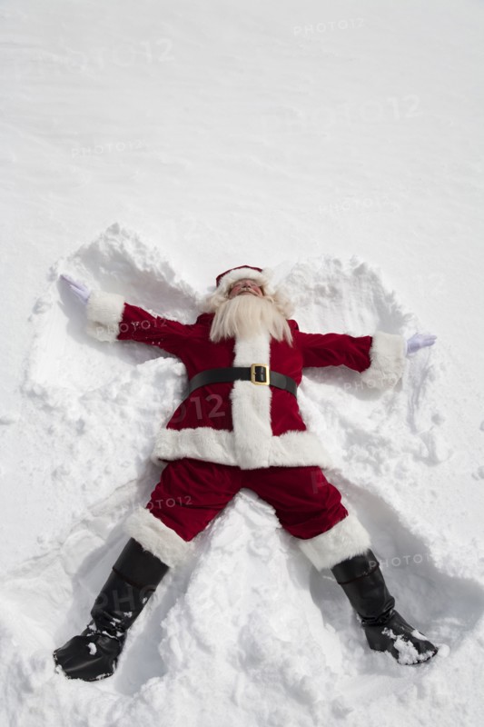 Santa Claus making snow angel outdoors