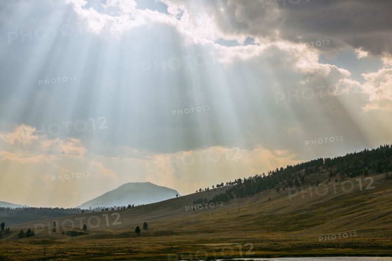 Sunbeams shining through clouds over rolling rural landscape