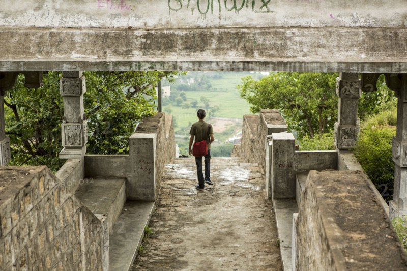 Man walking under stone walkway