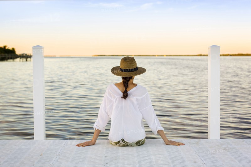 Caucasian woman sitting at edge of pier