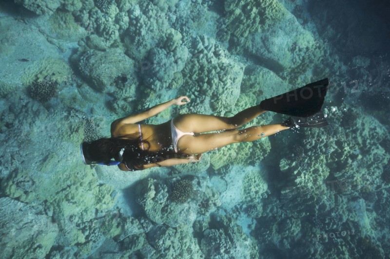 Mixed race woman snorkeling near tropical reef