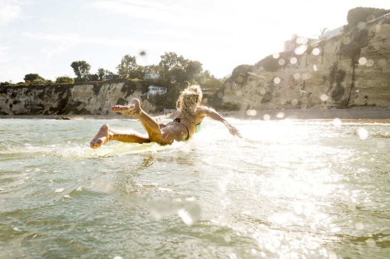Caucasian woman paddling on surfboard in ocean