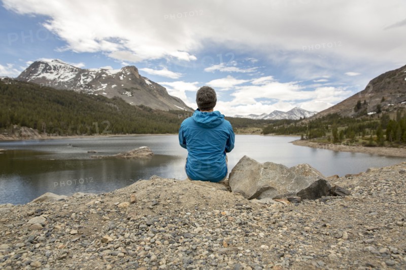 Caucasian man sitting on rock near lake