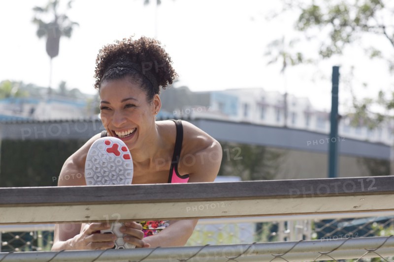 Mixed Race woman stretching leg on banister