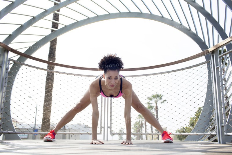 Mixed Race woman stretching leg near fence