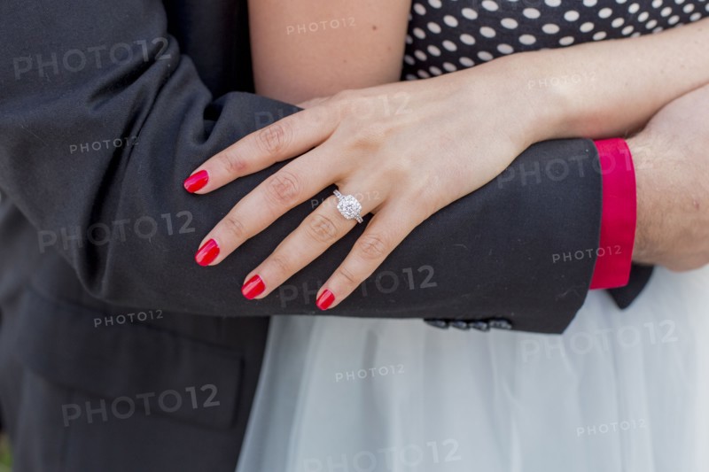 Man hugging woman wearing engagement ring on finger