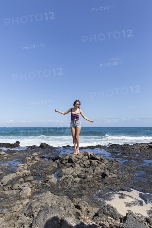 Mixed Race woman standing on rocks on beach