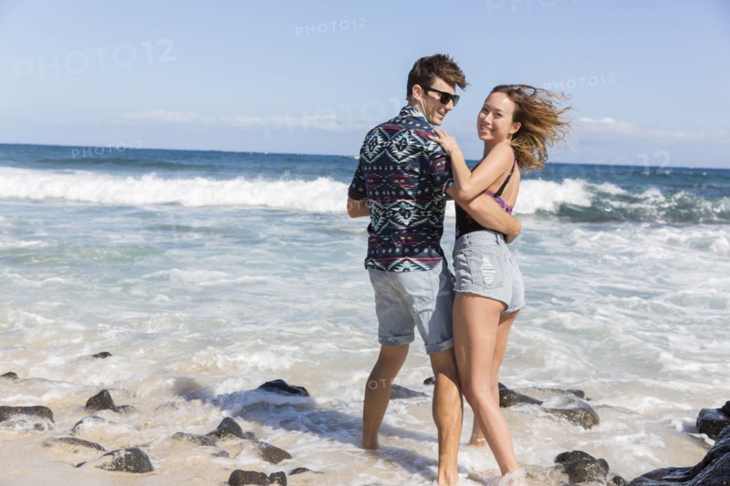 Smiling couple hugging on windy beach