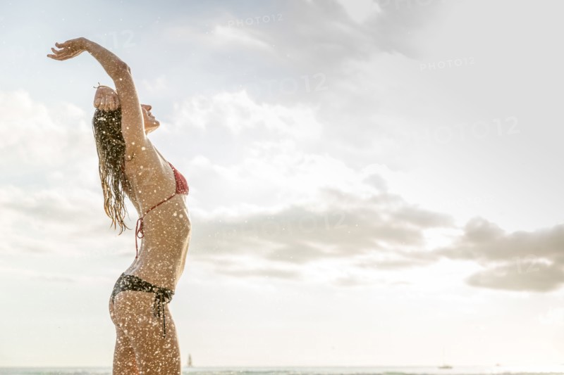 Ocean waves splashing on Caucasian woman wearing bikini