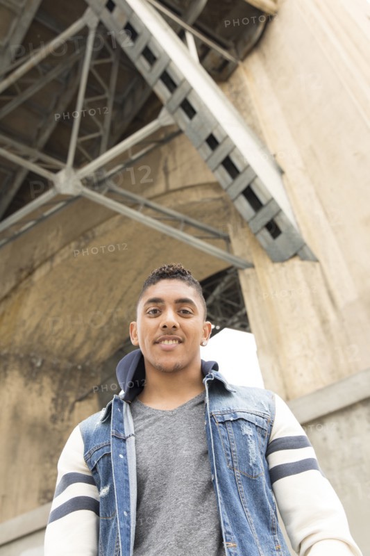 Portrait of smiling Mixed Race man under bridge