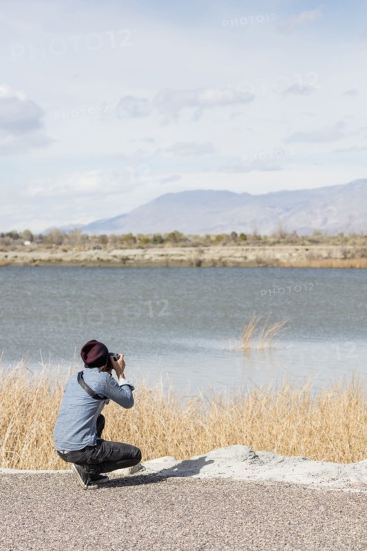 Caucasian woman photographing mountains at river