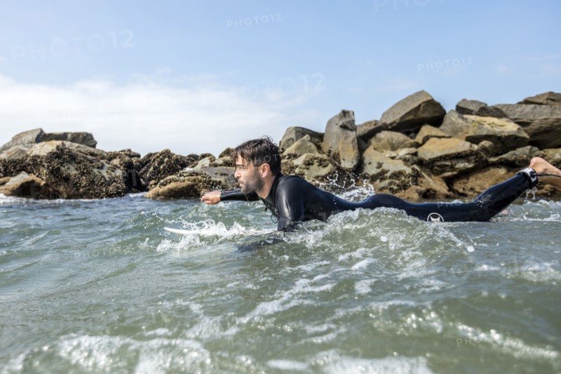 Caucasian man paddling on surfboard