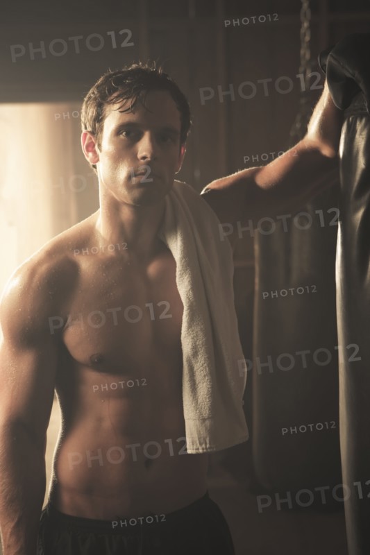 Fatigued boxer leaning on punching bag