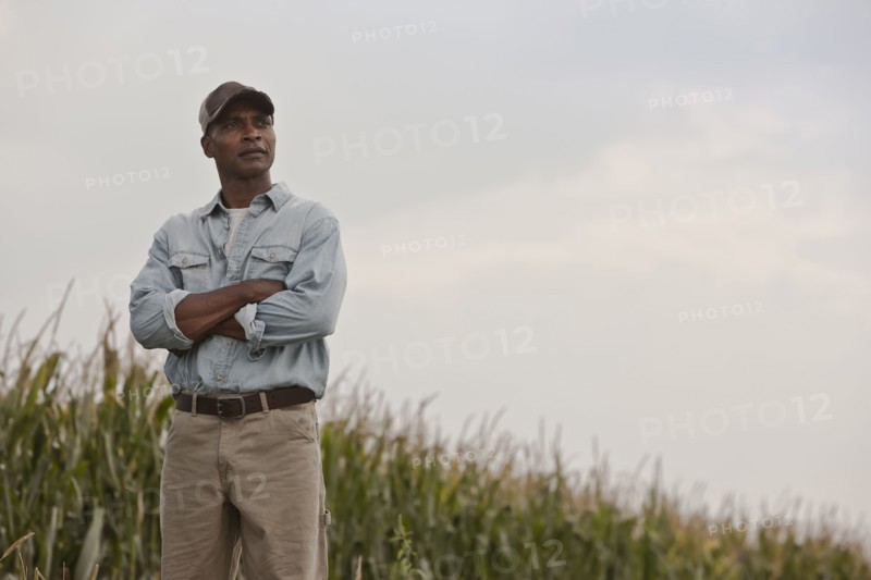 African American man standing in field with arms crossed