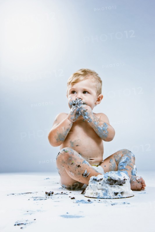 Caucasian baby eating birthday cake