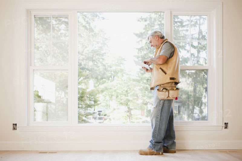 Caucasian carpenter using digital tablet in empty room