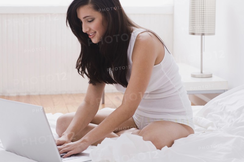 Mixed race woman using laptop in bed
