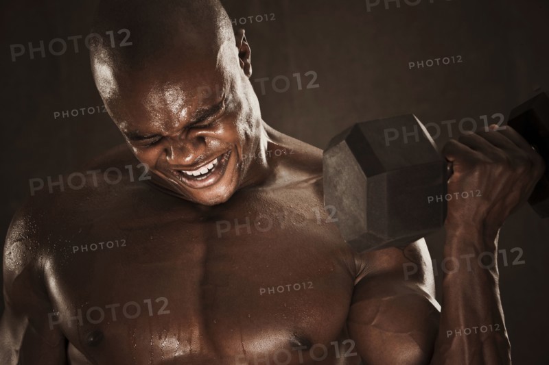 Grimacing African American man lifting weights