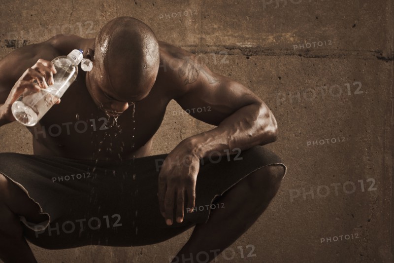African American man pouring water over himself after exercise