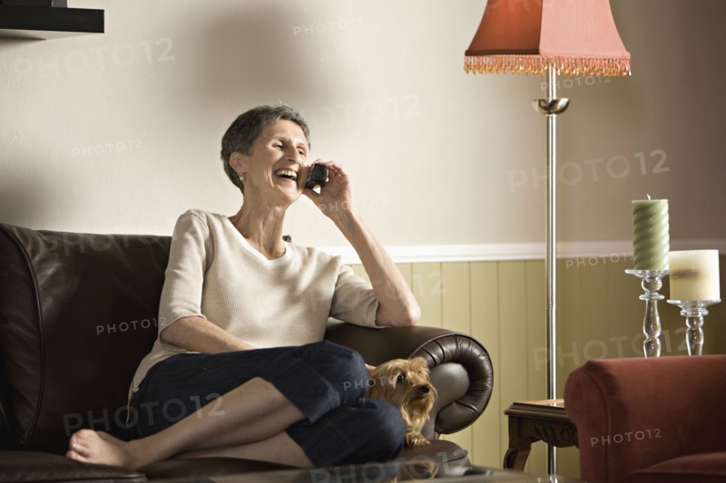 Senior woman sitting on sofa talking on telephone