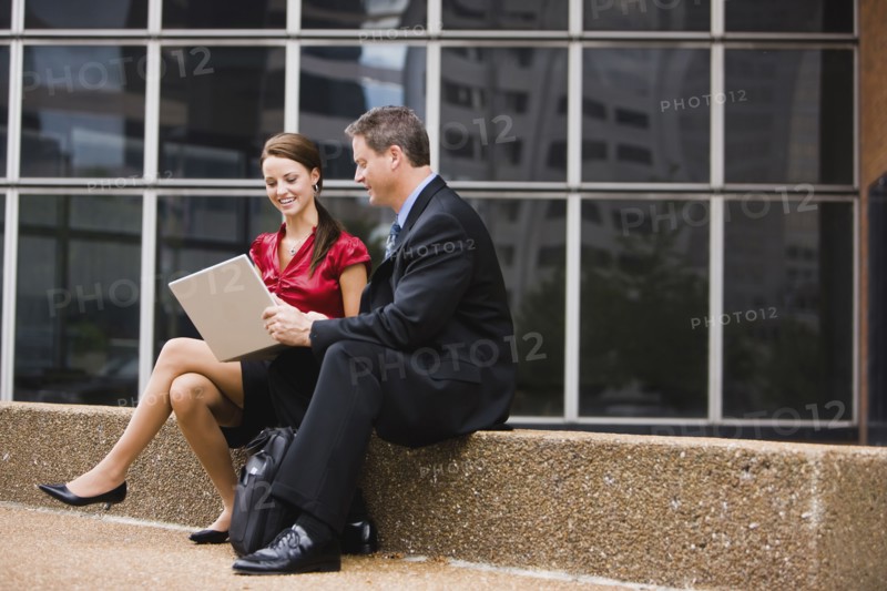 Caucasian co-workers using laptop together outdoors